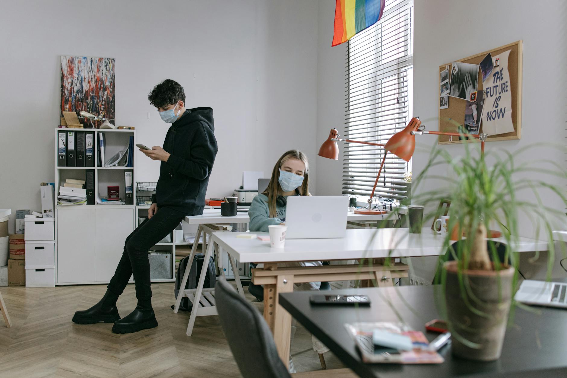 Dwie osoby w maseczkach pracują przy biurkach w nowoczesnym biurze