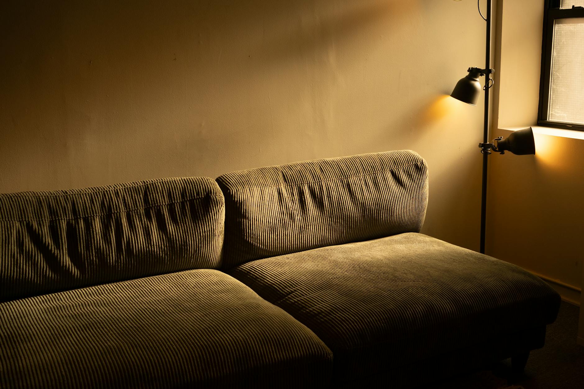 Sztruksowa sofa w nastrojowym, przyciemnionym salonie miejskiego mieszkania