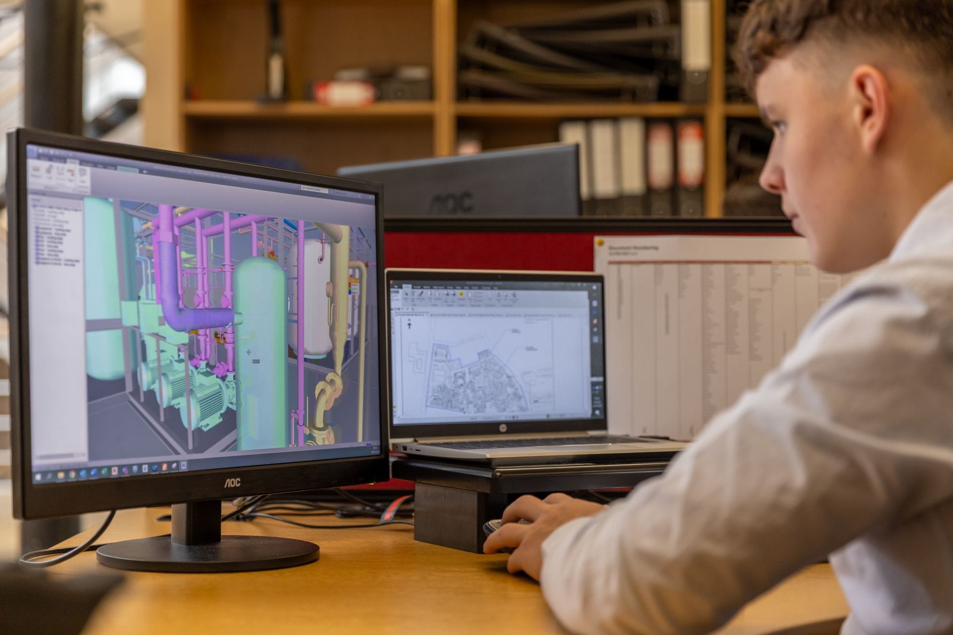 Inżynier przy dwóch monitorach z oprogramowaniem CAD w biurze