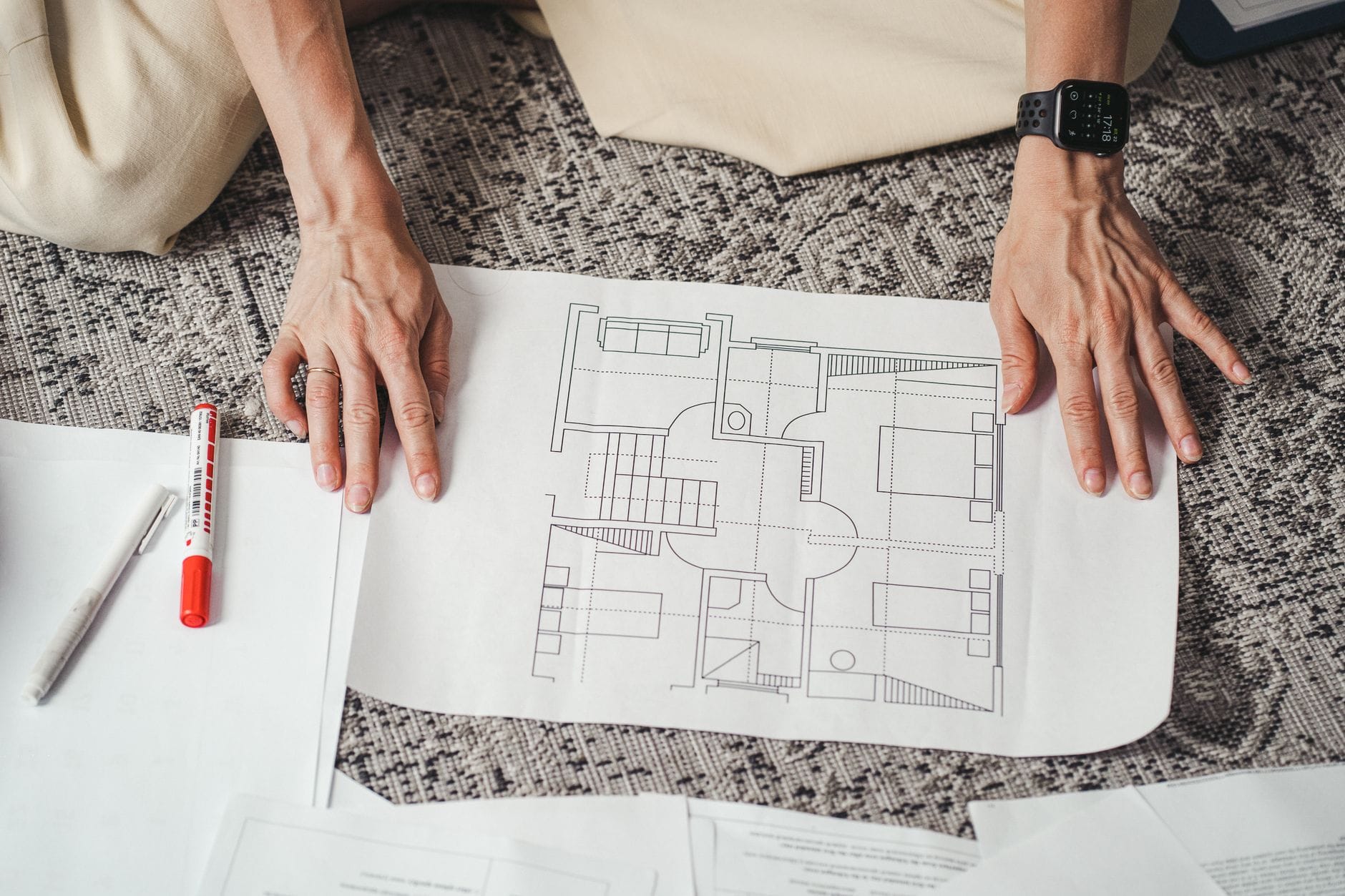 Dłonie nad szczegółowym rzutem architektonicznym domu na papierze