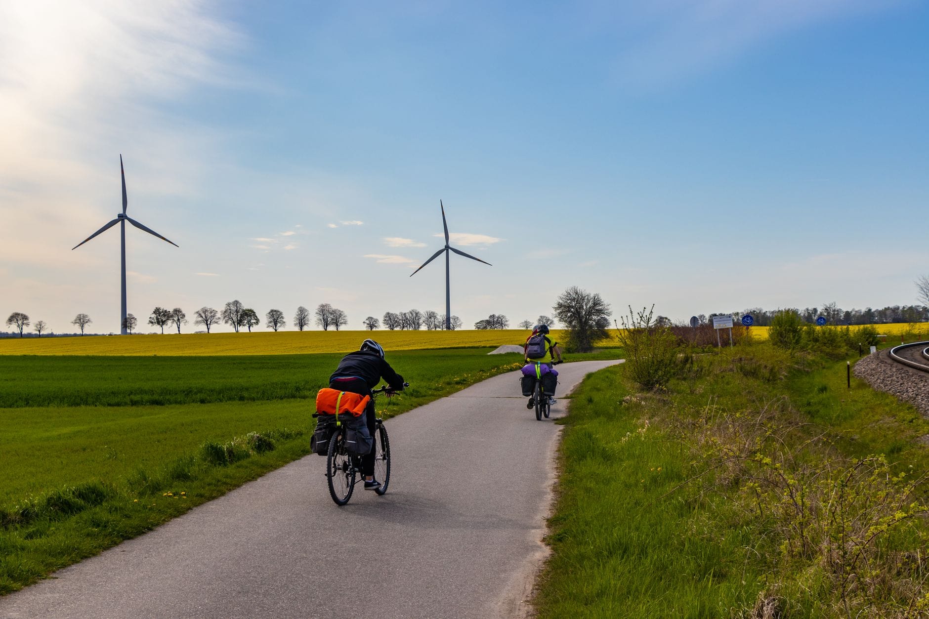 Dwóch rowerzystów na wiejskiej drodze obok wiatraków w słoneczny dzień