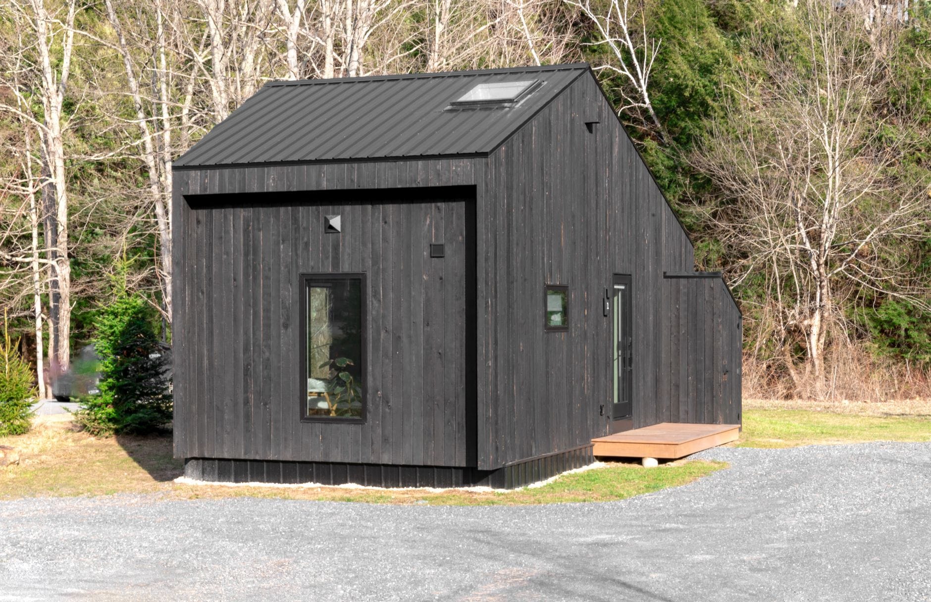 Małe działki, duże ambicje: strategie zabudowy, które maksymalizują komfort użytkowników Minimalistyczny czarny tiny house w lesie, przykład zrównoważonego życia