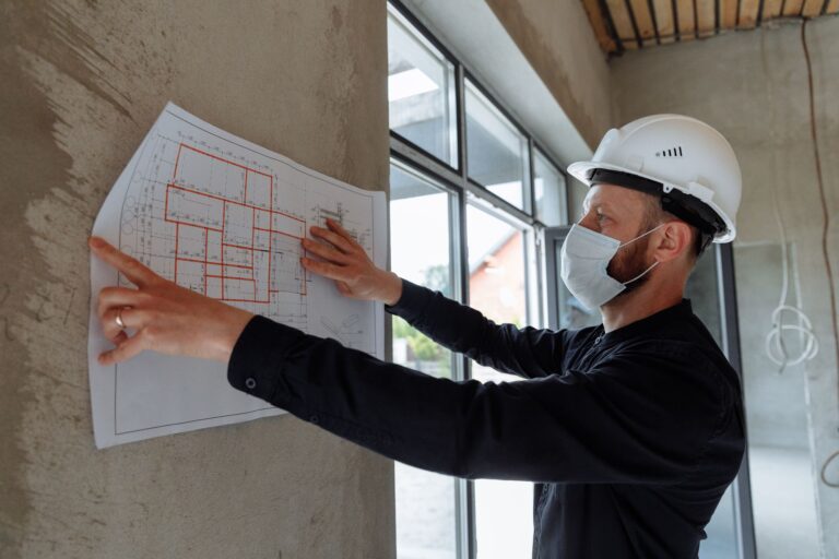 Architekt w kasku przegląda plany budowy na placu budowy
